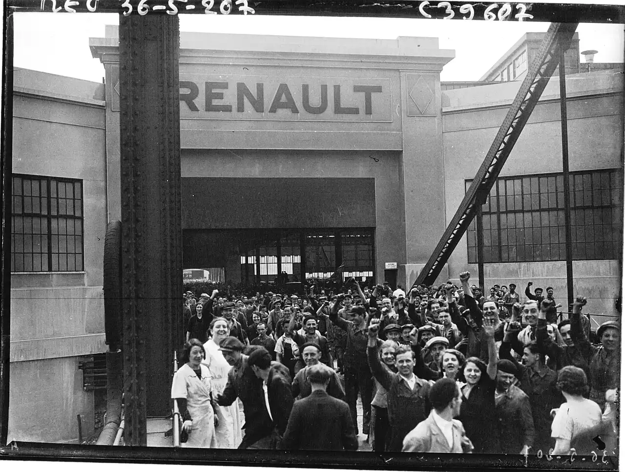 Une foule d'ouvriers et d'ouvrières, poings levés et souriants, sort par le grand portail d'une usine surmonté de l'inscription RENAULT.
